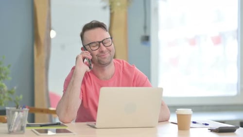 Adult Talking on Phone at Desk in Office