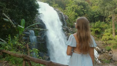 Woman Enjoys Waterfall View in Lush Tropical Forest
