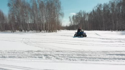 Man and Woman Riding ATVs on Snow Field