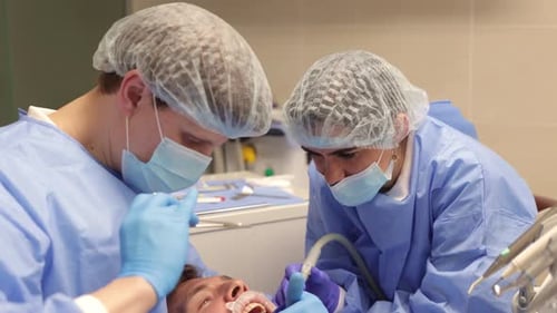 dentist and assistant suturing patient's gum