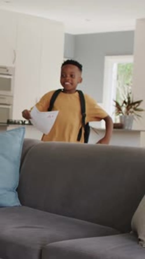 Vidéo verticale : Un élève entre dans la cuisine en tenant un papier pour indiquer sa note, l'élève et le transmet à ses parents