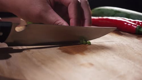 Hand Slices Scallions on a Wood Cutting Board