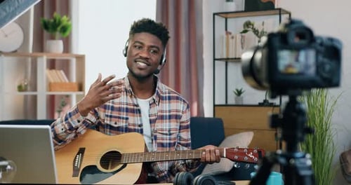 Man Vlogging Guitar Lesson with Camera and Laptop