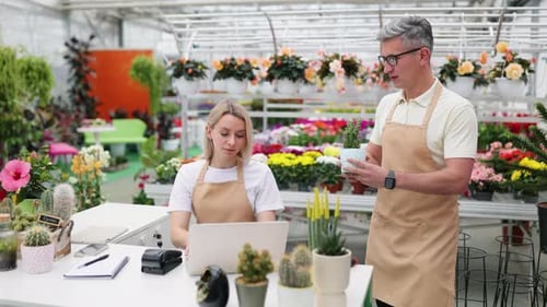 Florists Discussing Plant Sales in Greenhouse Setting