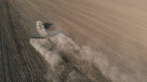 Aerial Survey Traktor bearbeitet Boden und fährt auf staubigem Feld