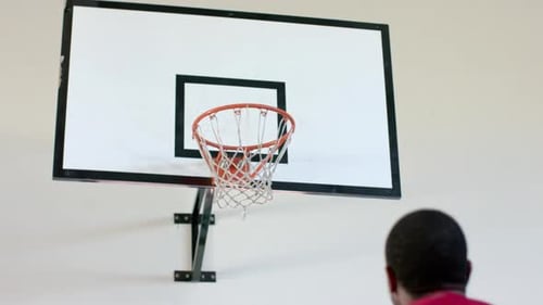 Young Adult Shooting Basketball Into Hoop Indoors