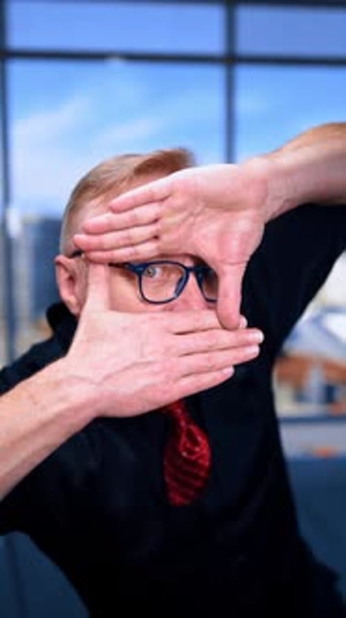Adult male looking through the window made with his fingers. Portrait of a man peeping at you.