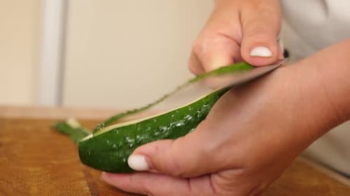 44. Cucumber is cut with a kitchen knife. We cook at home.