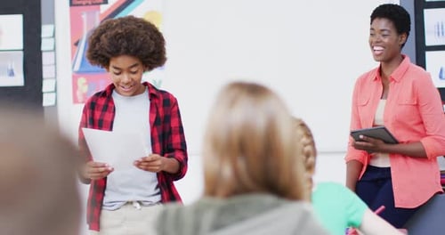 Professeure diversifiée et écolières heureuses à leur pupitre récitant en classe