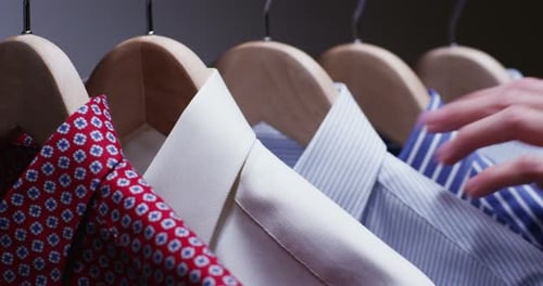 Shirts Hanging in Closet, Hand Adjusts Clothing