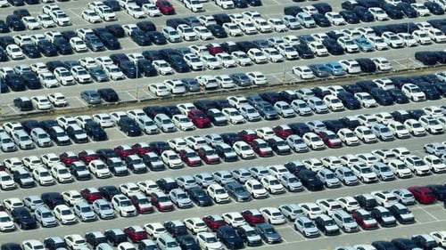 Rows of a new cars parked in a distribution center, by drone aerial view.