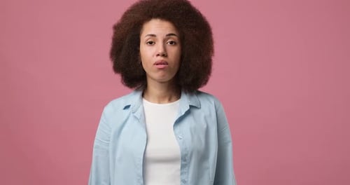 Woman with Curly Hair Expresses Confusion on Pink