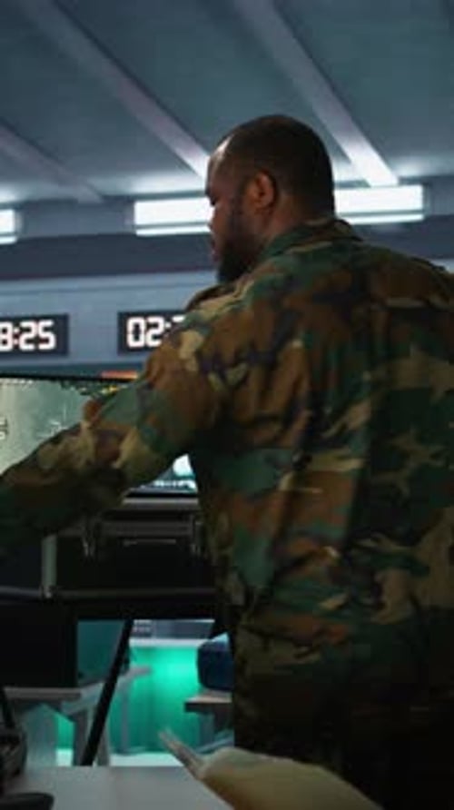 Men in Camouflage Discuss Strategy in Control Room