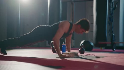 Man Performs Pushups on Red Mat