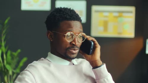 Young Black Businessman Having Conversation on Phone in Office