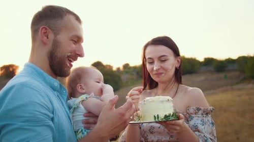 Happy Family with Baby Celebrate First Year Eat Cake in Field at Sunset Autumn and Lifestyle