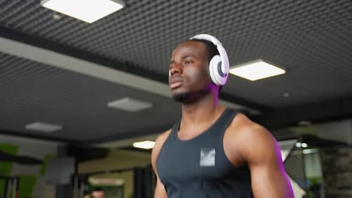 Fit Man with Headphones Exercising on a Running Machine at the Gym