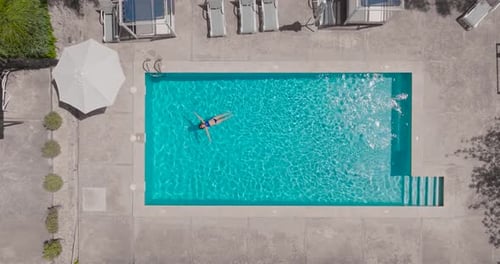 Top Down View of a Woman in Blue Swimsuit Lying on Her Back in the Pool