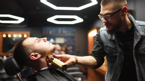 Bearded Barber Trimming a Young Man's Beard
