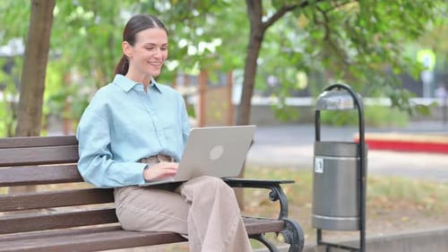 Woman Using Laptop on Bench during Video Call