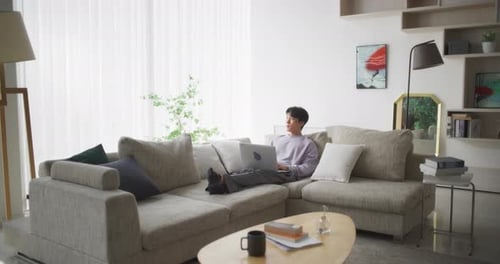 Young Adult Works Remotely at Home on Couch