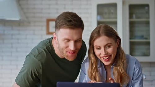 Happy Couple Looking at Laptop in Sunny Kitchen
