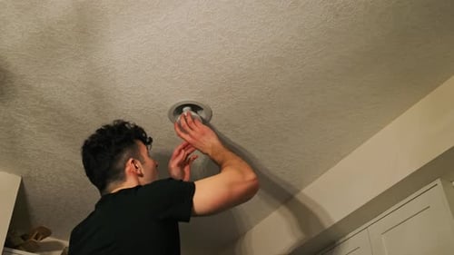 Man Installs Light Fixture in Home Ceiling