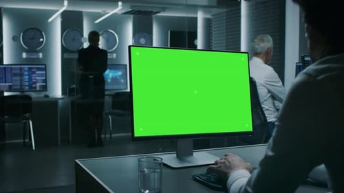 Rückansicht des Geschäftsmannes, der im Finanzgeschäft an einem Computer mit grünem Mockup-Bildschirm arbeitet