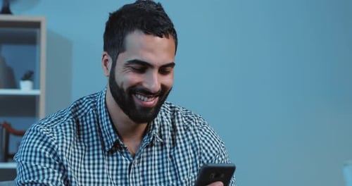 Smiling man using mobile phone indoors close up