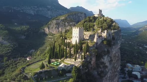 Drone 4k shot of an old castle fortress remains on top op a mountain in a small village Arco, close