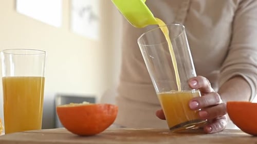 Woman Squeezing Fresh Orange Juice Into Glass
