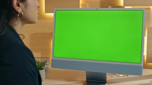 Woman Working at Computer with Green Screen Monitor