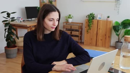 Young Joyful Woman Using Laptop Computer Sitting on Desk at Home Studio