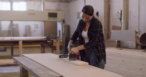 Woman Sands Wood in a Sunny Workshop