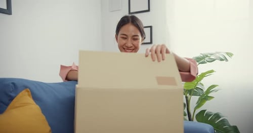 Woman Receives Package on Couch with Happy Surprise