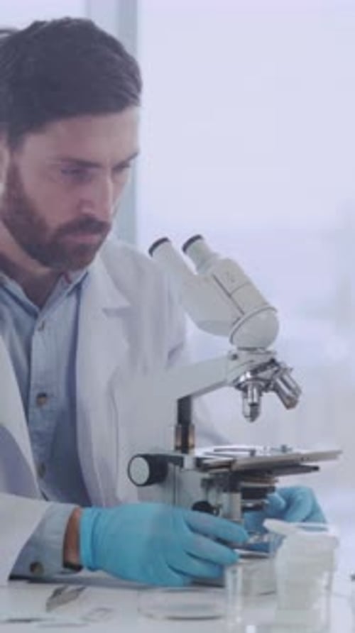 Man Working with Microscope in Lab Wearing Gloves