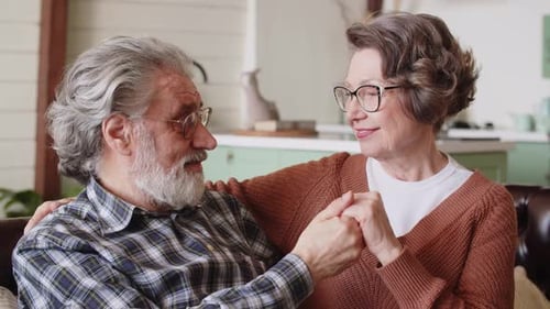 Loving Senior Couple Holding Hands Indoors