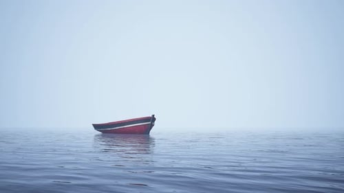Red Boat Drifting on Calm Misty Water