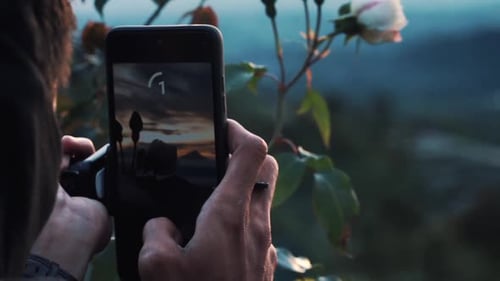 Person Photographing Sunset with Smartphone