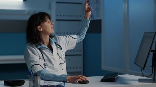 Female Doctor Analyzing X-Ray in Office at Night