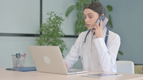 Young Female Doctor Talking on Phone in Clinic