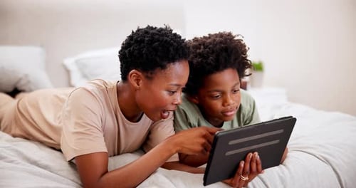 Woman and Child Using Tablet on Bed Together