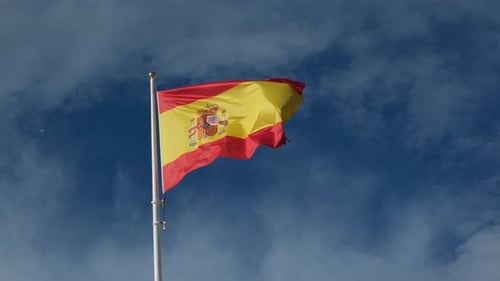 Spanish Flag Waving in Wind Against Blue Sky