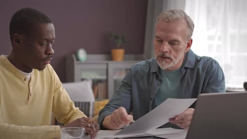 Men Reviewing Documents Together at Home Office