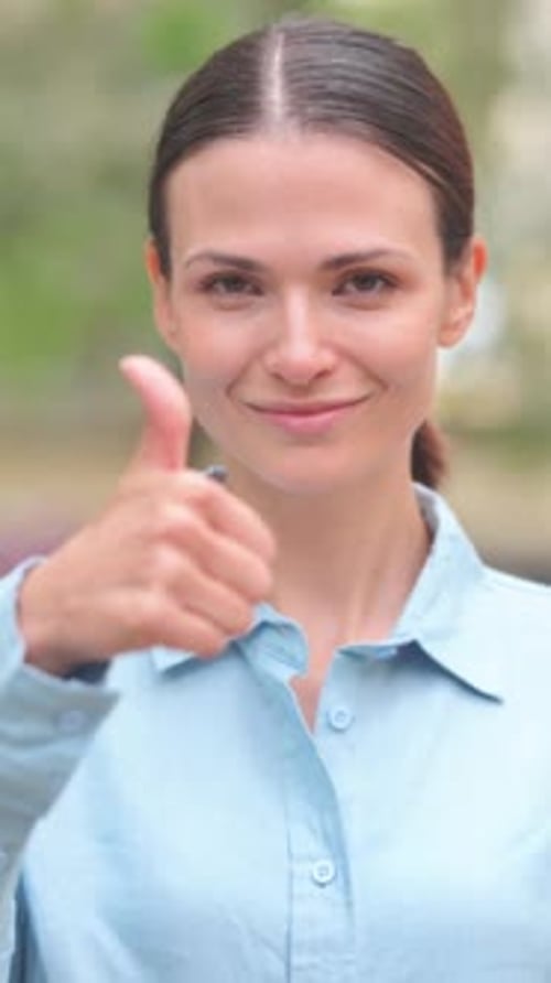 Smiling Woman Gives Thumbs Up in Outdoor Setting