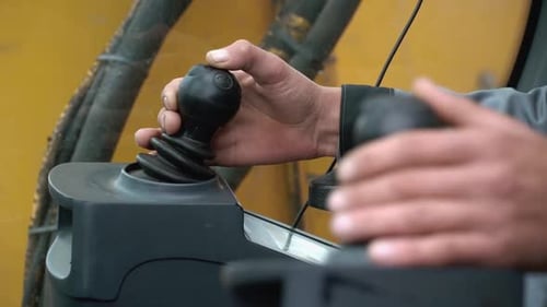 Erfahrene Hände beim Bedienen schwerer Maschinensteuerungen für Aufgaben im Bauwesen und in der Industrie