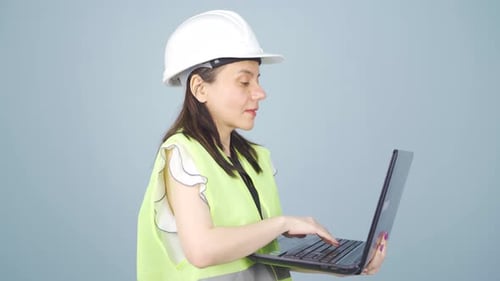 Engineer holding laptop laughing at camera.