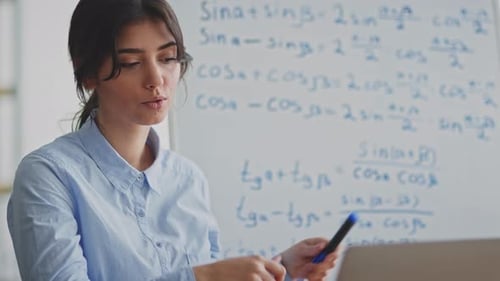 Woman Explaining Math Near Whiteboard and Laptop