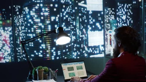 Man Working at Desk in City Office at Night