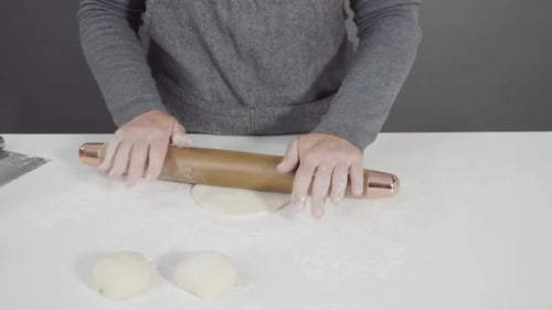 Person Rolling Dough on White Surface Indoors